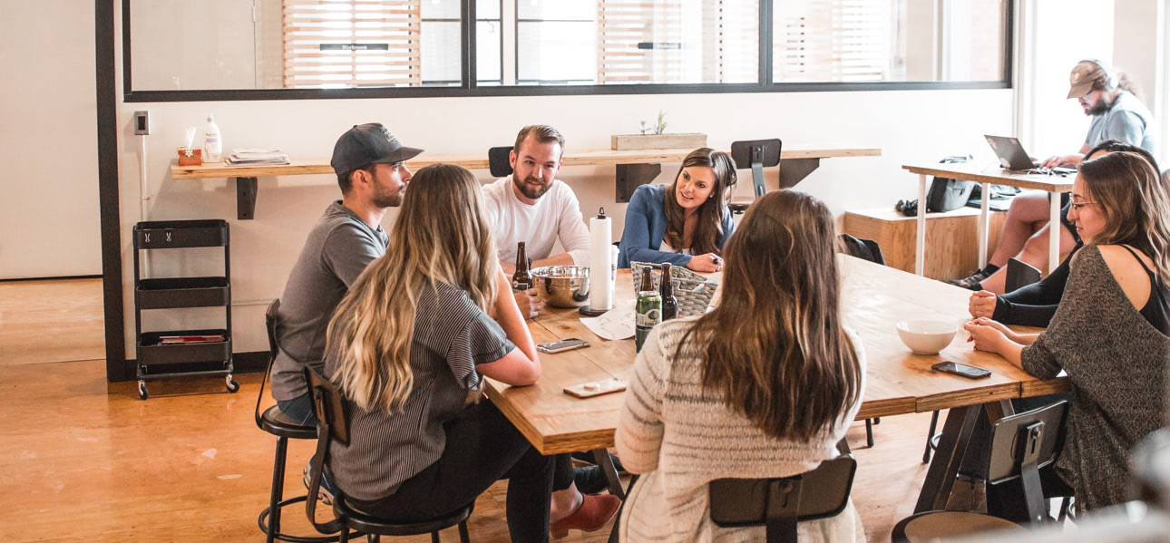 A group of people sitting around a table in an office, possibly discussing SEO strategies as part of their work at an SEO agency.