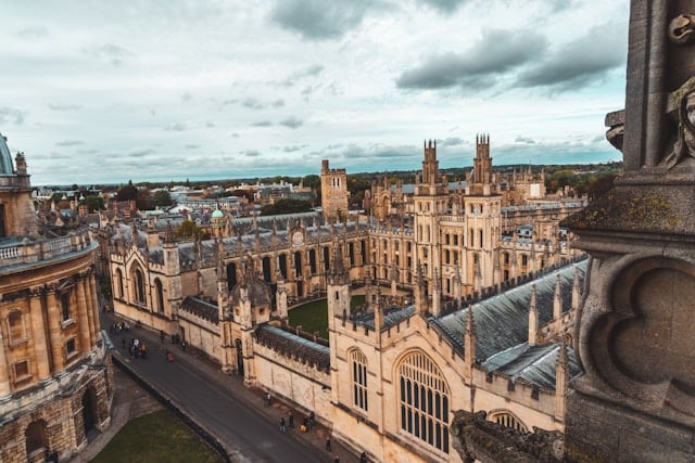Aerial view of historic stone university buildings with gothic architecture in Oxford, surrounded by roads and greenery under a cloudy sky—perfect inspiration for an SEO agency Oxford looking to blend tradition with innovation. seo agency london